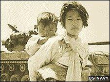 A Korean girl with her brother on her back in front of an M-26 tank in Haengju