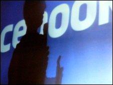 silouthette of someone in front of facebook sign