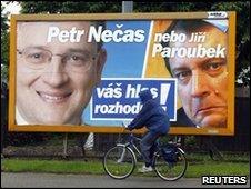 A man bicycles past an election poster for the Civic Democratic Party, featuring leader Petr Necas (left) and leader of the opposing Social Democrats Jiri Paroubek (right).