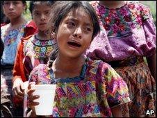 A child reacts as villagers recover bodies of two victims of storm in western Guatemala on 31 May 2010
