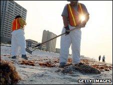 Workers clean-up oil on a beach in Pensacola, Florida