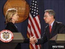 Hillary Clinton (left) and Alvaro Uribe shake hands at a news conference on 8 June