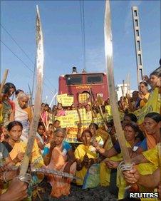 Protesters hold swords and sticks as they block a railway track in Patna, Bihar, on July 5, 2010
