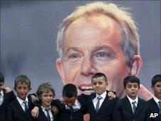 Nine children named after Tony Blair appear in front of a poster of the former prime minister in Kosovo
