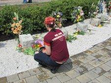 A Virginia Tech student kneeling in front of memorial stones