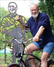 Michael Eavis poses beside a sculpture bench along the cycling route