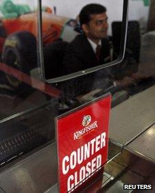 A Kingfisher Airlines employee sits behind a closed counter in Mumbai (March 2012)