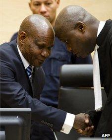 Mathieu Ngudjolo Chui (L) shakes hands with one of his lawyers at the ICC in The Hague on 18 December