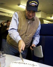 Leon Panetta cuts a cake that says 'arrivederci' on his final overseas trip as US Defence Secretary, aboard the E-4B on route to Washington, 19 January 2012