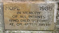 A small plaque which says in memory of all infants who died before at or after birth 