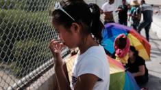 A Honduran girl waits with her family along the border bridge after being denied entry from Mexico into the US
