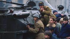 Romanian soldiers and civilians take cover behind a tank in Bucharest's Palace Square in December 1989