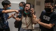 A woman reacts after she was hit with pepper spray deployed by police as they cleared a street with protesters rallying against a new national security law in Hong Kong