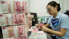 A Chinese bank employee counts 100-yuan notes and US dollar bills at a bank counter in Nantong in China's eastern Jiangsu province on August 28, 2019.