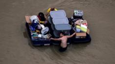 Un residente en Houston pasa por una calle inundada con sus pertenencias.