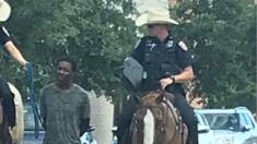 Two officers on horseback leading suspect on foot