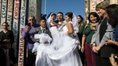 Bride Evelia Reyes and groom Brian Houston stand for a family portrait after getting married during a briefly reunited during the "Opening the Door of Hope" event at the border fence gate in Playas de Tijuana, Mexico on 18 November 2017.