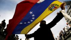 Hombre sostiene bandera venezolana durante una manifestación