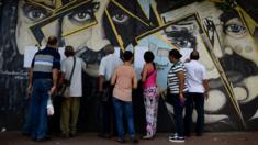 People look for their names on electoral rolls before voting in the municipal elections in Caracas on December 10, 2017.