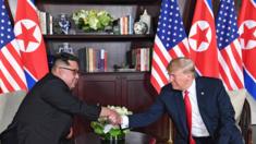 US President Donald Trump (R) shakes hands with North Korea"s leader Kim Jong-un (L) as they sit down for their historic US-North Korea summit