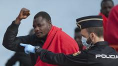 Un inmigrante de raza negra alza el puño mientras es custodiado por un policía español
