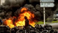 A fishermen from the French city of Boulogne walks past burning tyres blocking access to the port of Boulogne-sur-Mer on January 25, 2018,
