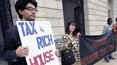 A man holds a sign saying Tax the Rich