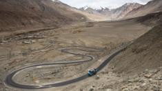 Workers ride on the back of a truck along Pangong Lake road in northern India's Ladakh region