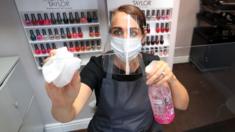 Roberta Dyer, owner of Roberta Beauty Redefined in Knutsford, Cheshire, wears PPE while she cleans a protective screen as they prepare to reopen following the further easing of coronavirus lockdown measures in England.