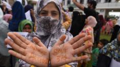 A Kashmiri woman shows her henna-painted hands with the slogans We Want Freedom and Save 370 during a protest, at Soura, on August 16, 2019 in Srinagar, India.