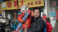 A man holds his son outside a toy store in China