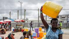 People wait to collect drinkable water delivered by local authorities after the cut on public supply of water that followed the passage of the cyclone Idai in Beira City, central Mozambique, 21 March 2019