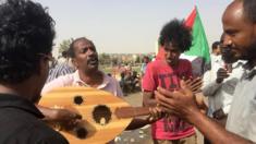 Sudanese play music as protesters gather in the streets of Khartoum and continue to rally demanding a civilian body to lead the transition to democracy one day after a military council took control of the country