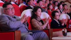A crowded theatre claps at something out of view - but in the front row sits North Korean leader Kim Jong Un, but Kim Kyong Hui can be seen seated two places to his left