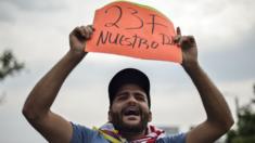 A man holds a placard reading "23F Our Day"