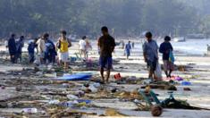People walk through debris along the shoreline of Patong beach of Phuket island, southern Thailand, 27 December 2004