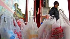 A shopper stands with free supermarket plastic shopping bags in Beijing