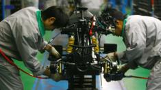 Workers labour on the production line of an all-terrain vehicle at the Chongqing Longcin Motorcycle Company on November 6, 2007 in Chongqing Municipality, China.