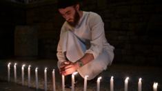 A well-wisher helps to light 49 candles as he pays respects to victims outside the hospital in Christchurch on March 16, 2019