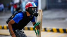 A protester wears a gas mask and shield in Venezuela