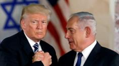 Donald Trump and Benjamin Netanyahu grasping hands in front of their national flags