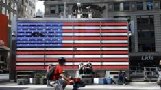 People are seen by the American flag in Times Square on May 22 in New York City