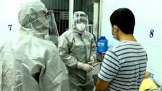 Nhân viên y tế trong trang phục bảo vệ trao đổi với bệnh nhân đã cho kết quả dương tính với virus corona trong phòng cách ly tại Bệnh viện Chợ Ray, TP HCM,hôm 23/1
