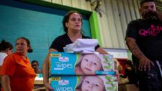 A woman carries boxes of baby wipes she removed from a warehouse filled with supplies in Ponce, Puerto Rico on January 18, 2020