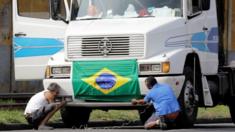Truck drivers arrange a national flag in front of their truck to attend a protest against high diesel prices, near the port of Santos in Santos, Brazil May 23, 2018.