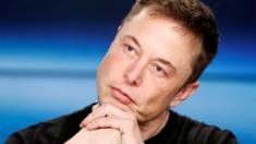 Elon Musk listens at a press conference