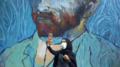 A woman takes a selfie with a large mural of Van Gogh
