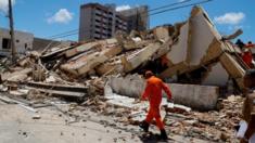 A rescue worker walks past the rubble of a building which collapsed in Fortaleza