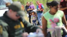 Central American asylum seekers wait as US border patrol agents take them into custody on 12 June 2018 near McAllen, Texas