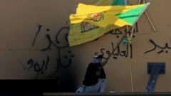 Man waves a Kataib Hezbollah flag outside US embassy in Baghdad (file photo)